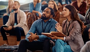 Professionals attending a business seminar, taking notes and listening attentively.