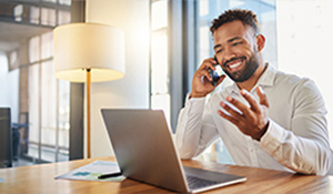 Businessman smiling while on a cell phone and working on a laptop