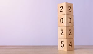 A stack of four wooden blocks. The top three blocks show '202' while the bottom block is transitioning between '5' and '4', symbolizing the change from the year 2024 to 2025.