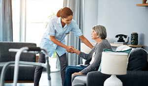 Home healthcare worker assisting an elderly woman in a cozy living room